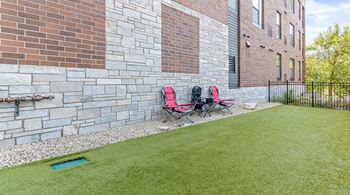 Two red chairs are placed on a green lawn.